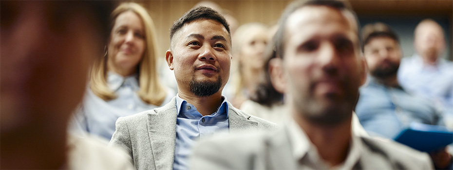 Attendees listen attentively during the OHSU’s Symposium on Educational Excellence. A man in a gray blazer is focused on the presentation among other engaged participants.