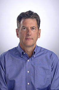 Steve Stadum smiles in a blue button-down shirt