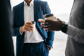 Professional leader speaks with young professionals over coffee.