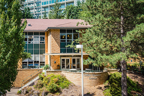 Trees frame the sides of the entrace to the OHSU Student Center building. 