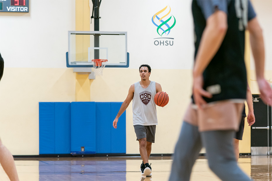An OHSU student dribbles a basketball during an intramural game.