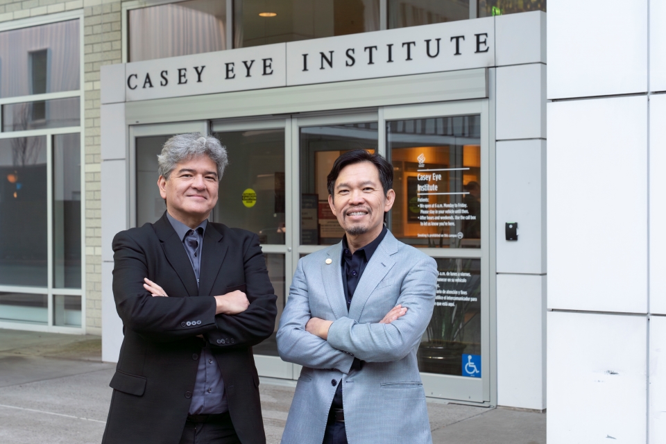 Photo of Dr. Andreas Lauer and Dr. David Huang posing for the camera in front of the Casey Eye Institute building.