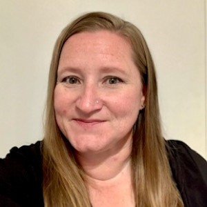 Emily, a woman with long, blonde-brown hair, black shirt, and a slight smile.