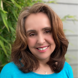 Sandra, a middle-aged white woman with brown hair and brown eyes wearing a blue top in an outdoor setting