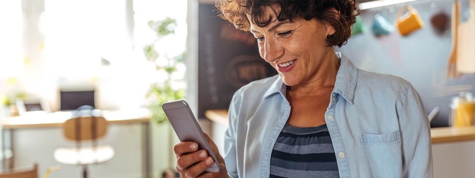 A woman smiles looking at her cell phone.