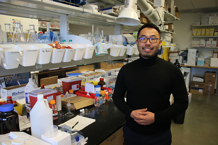 A male researcher stands in a laboratory smiling.
