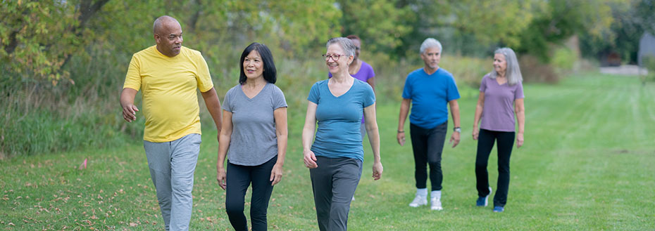 A diverse group of adults walks across an expanse of lawn.