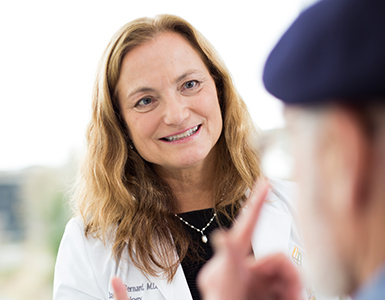 OHSU neurologist Jacqueline Bernard, M.D., FAAN talks to an older male patient whose face we can't see