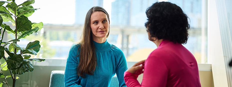 Social worker Andrea Lehman listens to a person as they sit together in a sunlight-filled room.