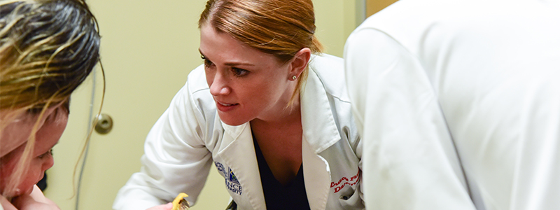 A woman doctor speaks with a child during a patient visit