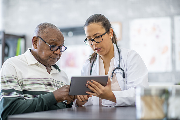 Young female doctor shows an elderly man the screen on a computer notepad. 