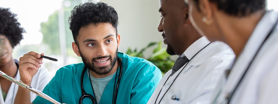A young male doctor consults with two senior doctors in a meeting room