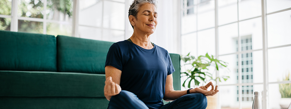 Middle-aged woman meditates in her living room