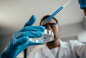 Young scientist drops fluid into a dish to analyze