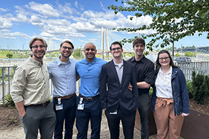 Students in the M.S. in Medical Physics cohort at OHSU  Alt text: M.S. in Medical Physics students at OHSU stand together outside with a view of the Tilikum Crossing Bridge behind them.