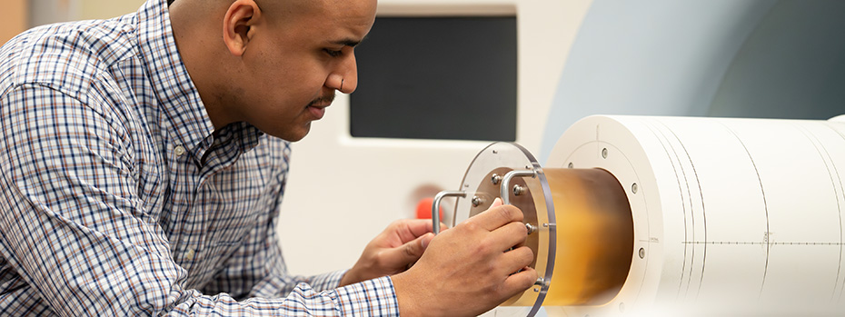 OHSU medical physics student, Marc Dennis, adjusting equipment on a phantom device used for quality assurance testing.