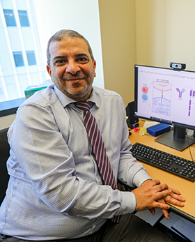 Portrait Dr. Nizar Chahin sitting at his desk smiling at the camera.]