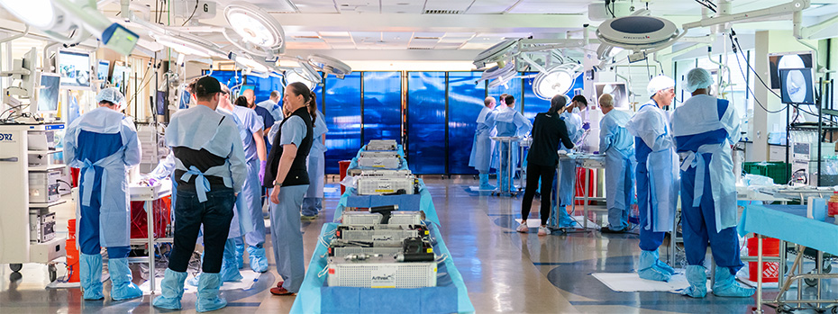 OHSU health care teams in surgical gowns and scrubs practice procedures in a large, fully equipped surgical simulation lab.