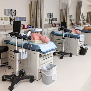 Multiple patient care stations equipped with adult manikins, monitors and medical supply carts in the Multnomah Pavilion Simulation Center at OHSU.