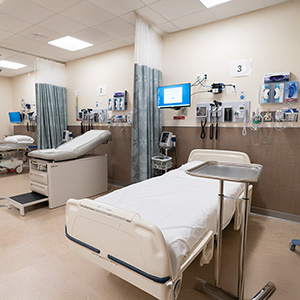  Two unoccupied patient care bays in a clinical simulation lab at an OHSU regional campus, each equipped with a bed, wall-mounted diagnostic equipment, a monitor and privacy curtains.