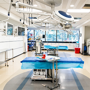A simulated operating room at the VirtuOHSU Simulation and Surgical Training Center, equipped with a draped procedure table, overhead surgical lighting and medical supply stations.