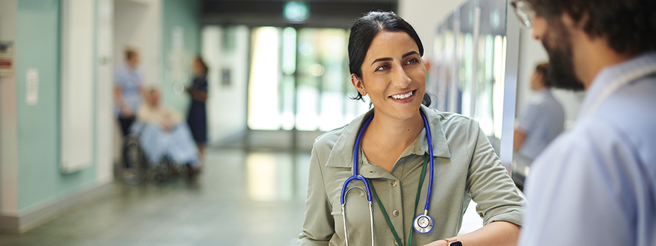 Female doctor chats with a male colleague in a hospital hallway.