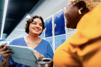 Two OHSU students sit across from each other smiling while reviewing a document.