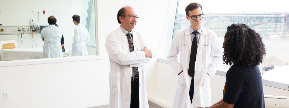 Dr. Charles D. Lopez, a professor of medicine at OHSU, and Jeff Donovan, a physician assistant, talk with a patient in a medical exam room. 