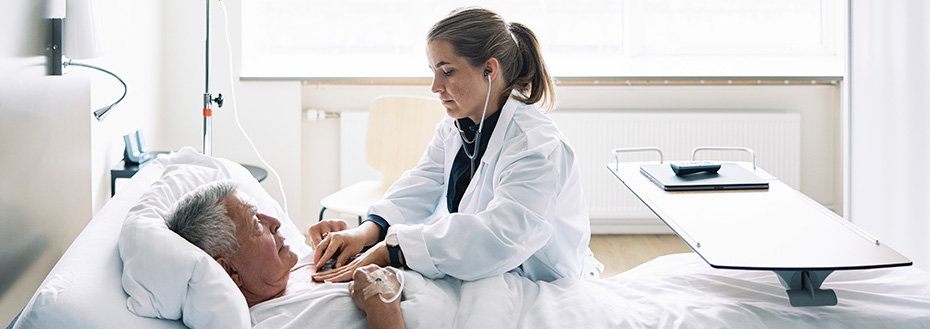 A female doctor checks the pulse of a senior patient in a hospital ward.