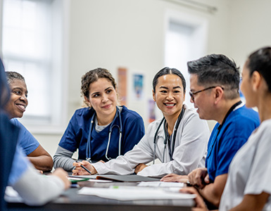  A group of fellows discuss a patient case around a conference table.