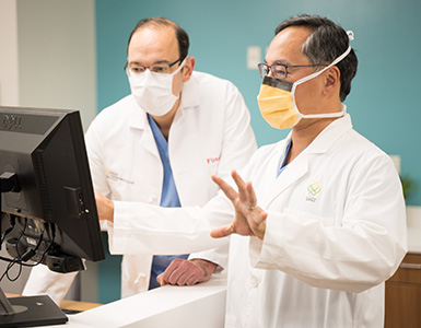 OHSU cardiothoracic surgeon Howard Song, M.D., Ph.D., gestures at a computer screen while talking to Firas Zahr, M.D.