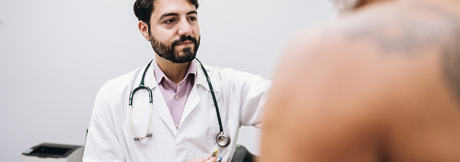 A doctor puts sensors on a male patient’s chest to monitor his heart.