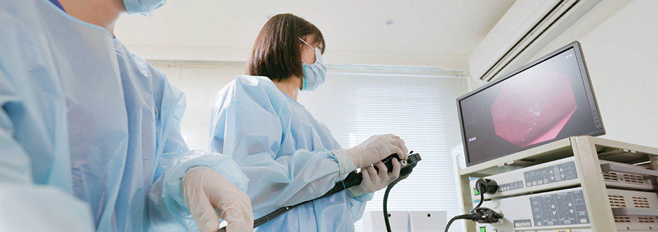 A doctor performs a colonoscopy on patient in a hospital room.