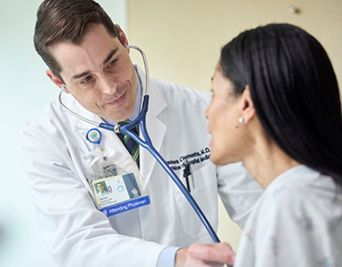 OHSU hospitalist James Clements, M.D.,FACP, listens to the heartbeat of a female patient.