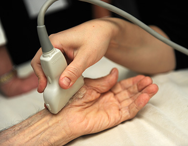 A medical professional uses an ultrasound to examine a patient’s wrist.