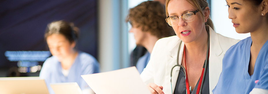 Doctors discuss research together while working at a conference table.