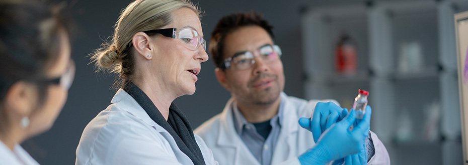 A small team of medical lab staff are seen working together in a research lab.