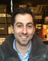 A man smiling in front of a shelf in a lab.