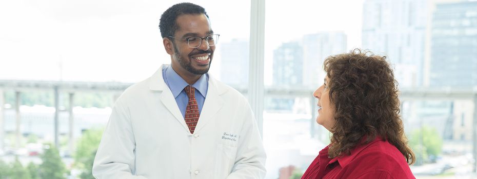 Dr. Donn Spight, a surgeon at OHSU, consults with a patient at OHSU in front of a large window overlooking Portland.