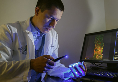 A OHSU scientist inspects a sample with a light device.