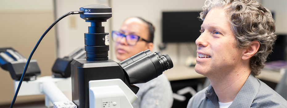Dr. Phil Raess (right), associate professor of pathology and laboratory medicine and medical director of hematopathology, and Dr. Raidelys Avila Diaz, a hematopathology fellow at OHSU, sit near lab equipment while attending a clinical conference.