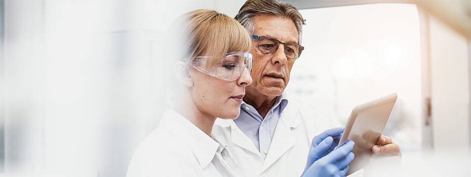  A PA student in a white lab coat reviews data in a lab alongside faculty.
