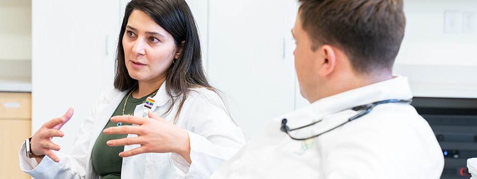 Faculty speaks with a student in a clinical setting.