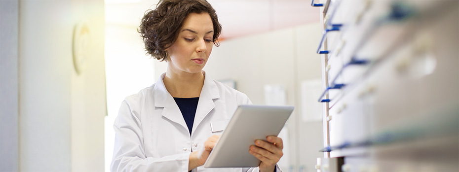 A PA student in a white coat reviews information on a tablet