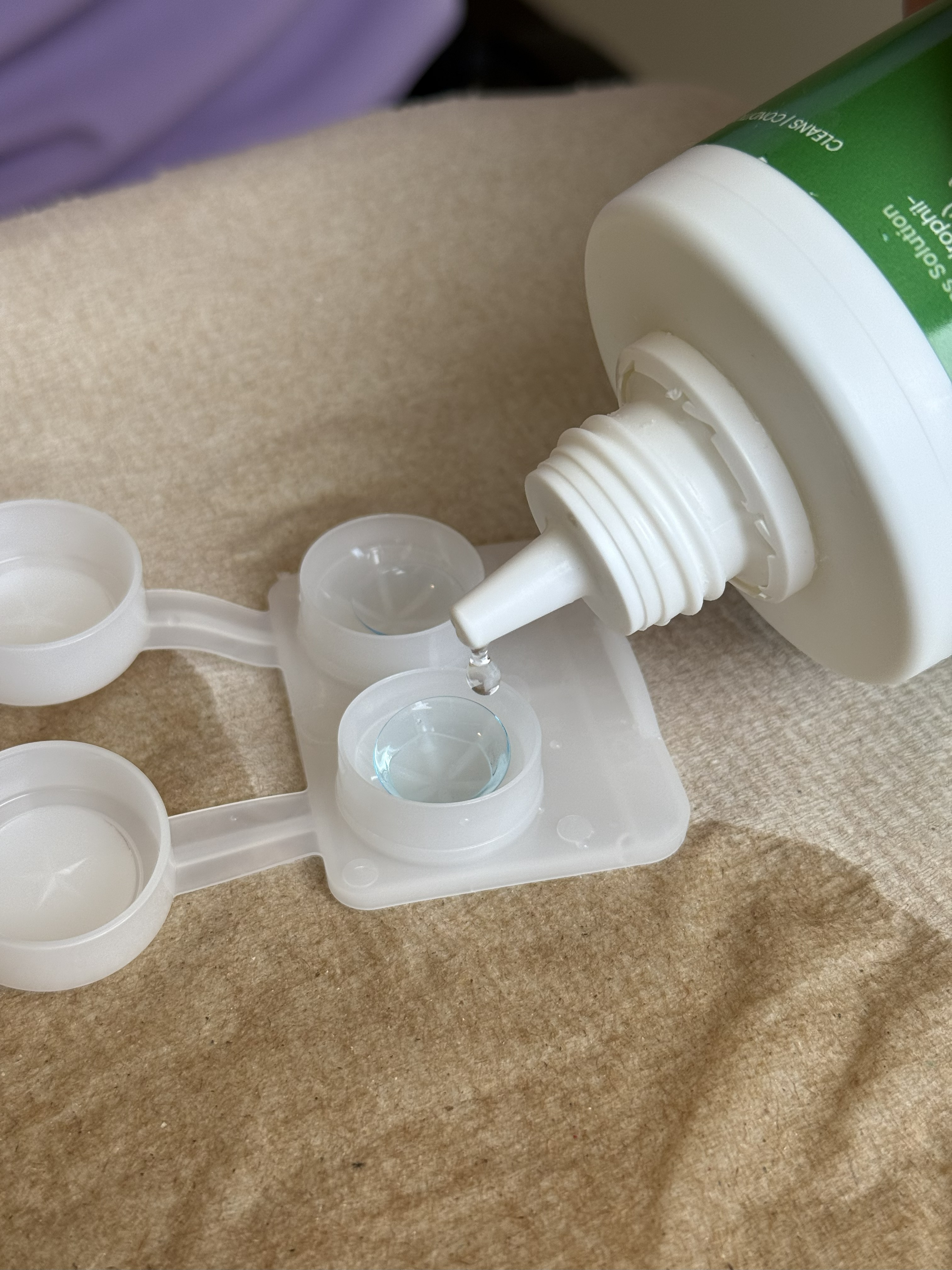 Close photo of a contact lens cleaning case with a lens inside being filled with cleaning solution.