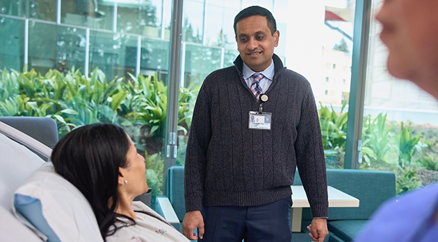 A doctor stands at a patient’s bedside.