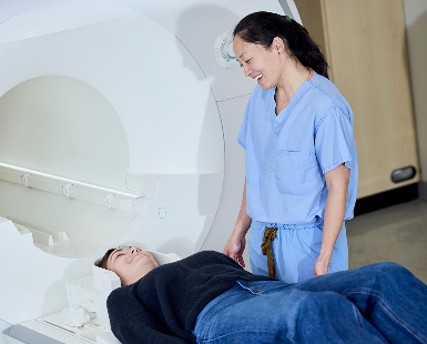 Dr. Erin Yamamoto  (in scrubs), an OHSU neurosurgery resident, prepares a patient for the MRI machine in the Piantino Lab.