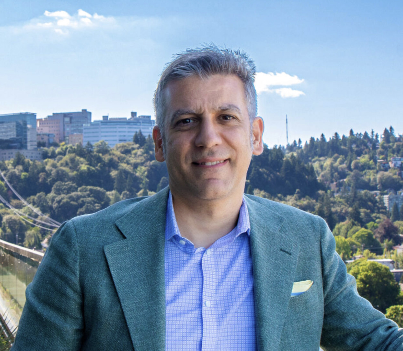 Dr Steve Mansoor stands in front of view of OHSU campus