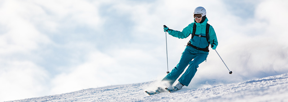 An adult woman skis down a mountain.