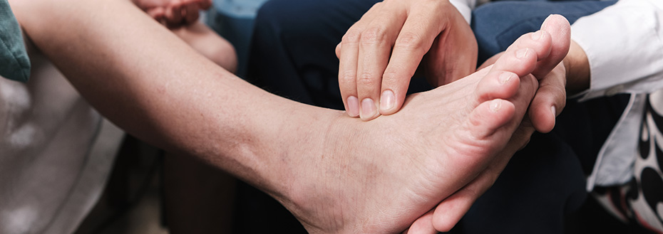 A doctor wearing a white coat examines a patient's foot.